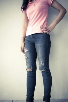 Young fashion woman legs in jeans, vintage tone background