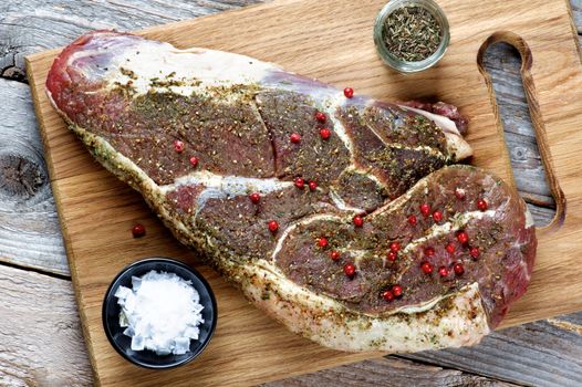 Perfect Big Raw Beef Steak with Spices, Salt Flakes and Thyme on Wooden Cutting Board Ready to Roast closeup. Top View