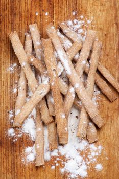 Heap of Freshly Baked Whole Wheat Bread Sticks with Dough closeup on Wooden Cutting Board