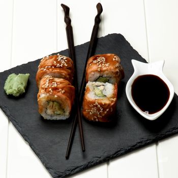 Delicious Smoked Eel Sushi with Soy Sauce, Wasabi and Chopsticks on Stone Plate closeup on White Plank background