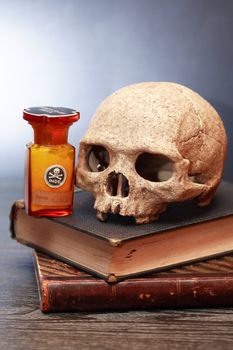 Medical laboratory. Human skull on old book near flask with poison