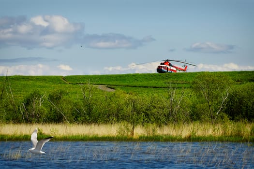 red resque helicopter on green grass with blue sky background