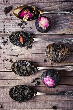 Tea with four spoons of different sorts of tea on wooden background