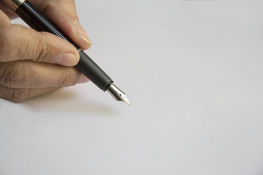 Hand holding a black pen on a white sheet of paper in the position of writing