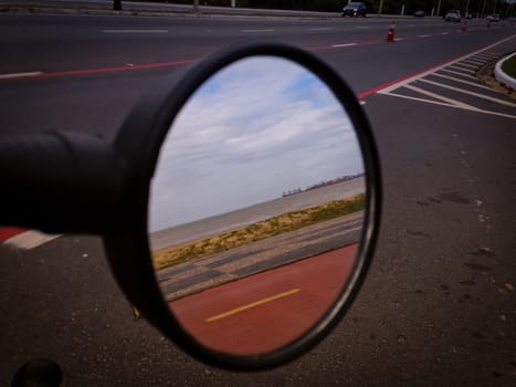 Side mirror view of red road and beach