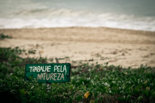 Sign on the beach wich says to work for nature in portuguese language