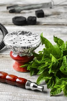 Eastern hookah with mint flavor of tobacco on a light wooden background