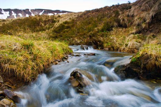 Stream among melting snow in a Carpathian Mountains