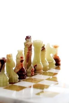 Set of chess pieces made from Onyx on board against white background