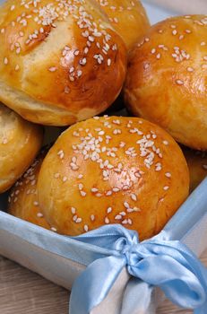 Buns with sesame seeds in a basket on table
