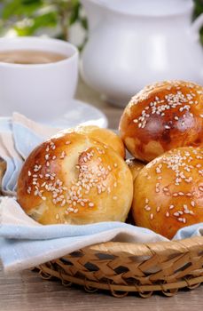 Buns with sesame seeds in a basket on table