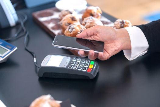 Making contactless payment in cafe with mobile phone.