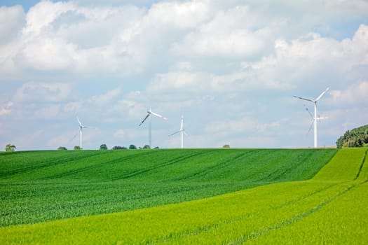 Green field, farmland with windmills and sky with clouds