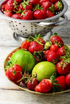 Harvest rustic strawberry and lime fruit on light background
