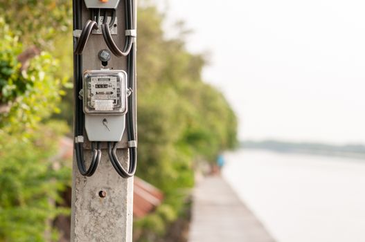 Electricity meter installed in the atmosphere of the waterfront in thailand