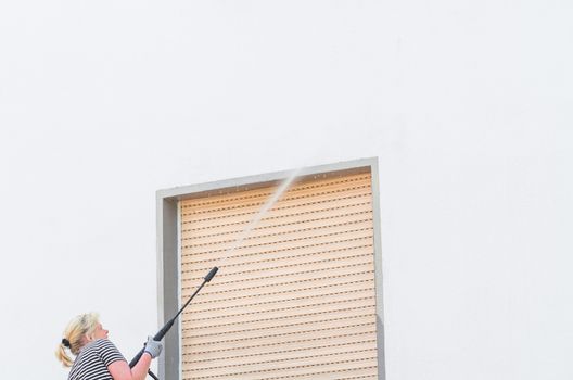 Exterior cleaning and building cleaning a gable wall with high pressure water jet.