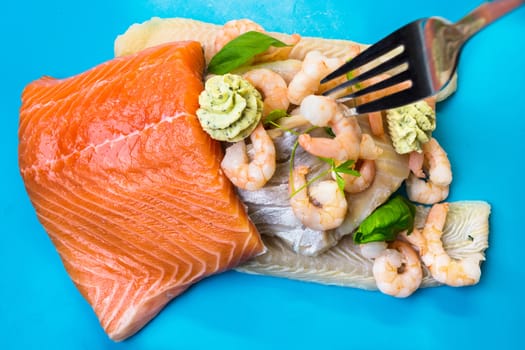 Various raw fish species as fillets like salmon, cod and shrimp.