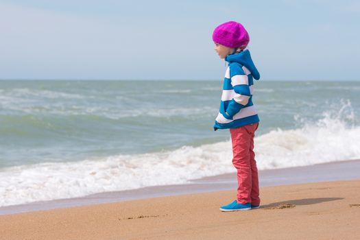 Girl standing on sea beach and looking into the distance