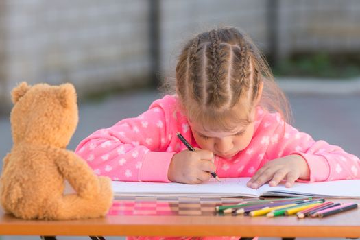 Offended girl draws a hunched figure in the yard