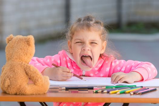 Girl shows the language in the frame drawing in the yard
