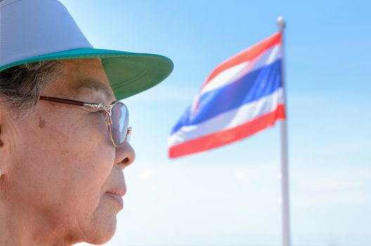Face side old women Thai people and Thailand flag on a blue sky background