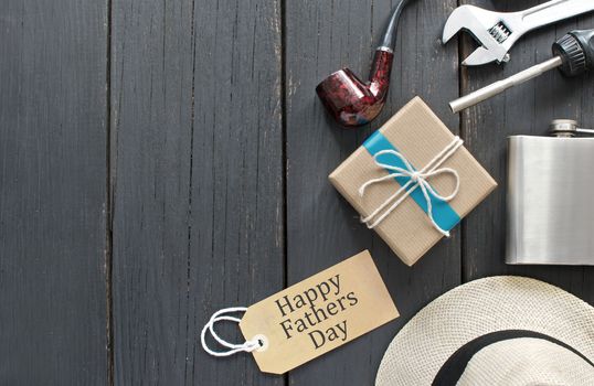 Fathers day gift box tied in blue ribbon over a wooden background with label