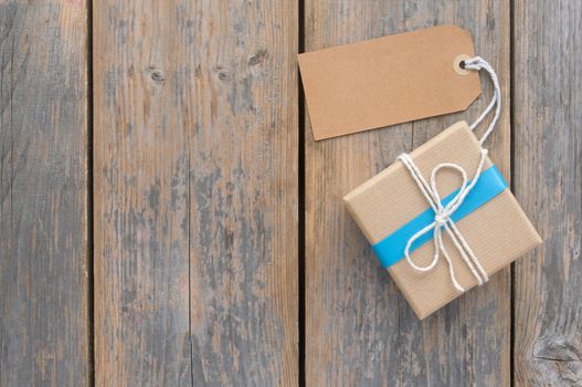 Gift box tied in blue ribbon over a wooden background