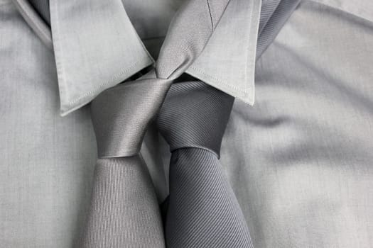 Two gray ties tied in knot round a collar of a gray shirt