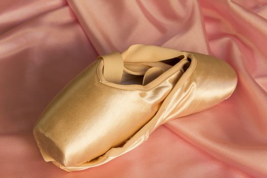 Ballet shoes on delicate pink silk background
