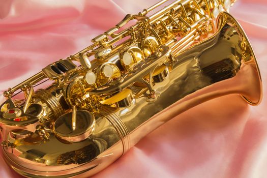 beautiful golden saxophone on delicate Pink silk background