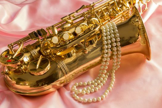 Saxophone and Pearl necklace on Pink silk fabric soft
