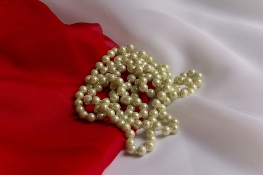 Pearl necklace on a background of delicate white and red silk