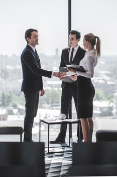 Business people sitting near panoramic window with view on city and talking