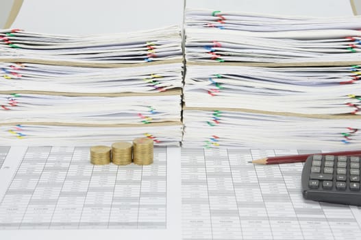 Brown pencil with step pile of gold coins on finance account have overload of paperwork with colorful paperclip and envelope with calculator as background.