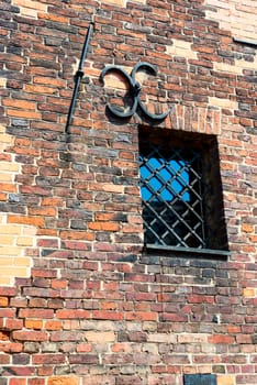 Small barred window in an old brick wall. The metal bars of the window in the form of an arch