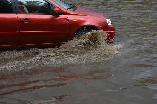 Car rides in heavy rain on a flooded road