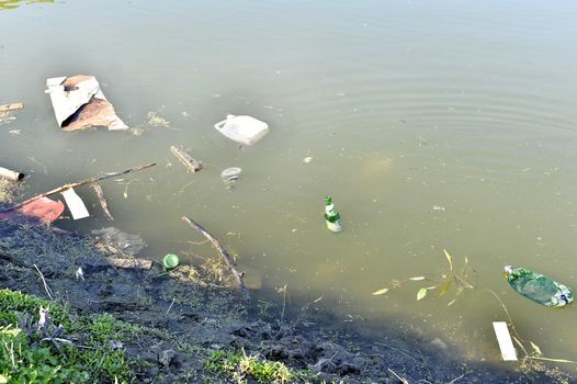 Rubbish, waste floating in polluted pond.
