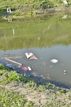 Rubbish, waste floating in polluted pond.