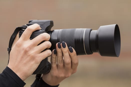 girl with beautiful manicure photographs on single-lens reflex camera