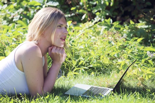 Woman working on a laptop outdoors in summer garden