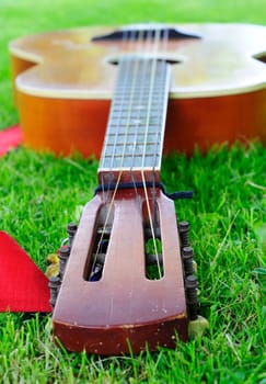 Closeup of old guitar laying on the grass.