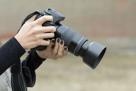 girl with beautiful manicure photographs on single-lens reflex camera