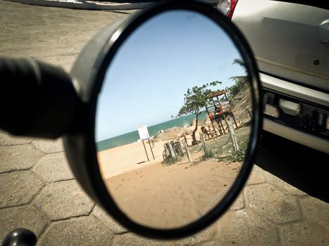 beach reflected on the side mirror of a motorcycle