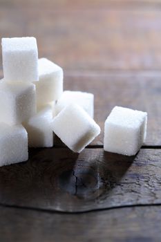 Stack of sugar cubes on wooden board against light