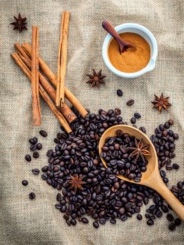 The Cup of coffee beans on the cloth sack with cinnamon sticks ,cinnamon powder in the bowl and star anise.