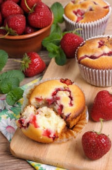  Break muffin with strawberries on a table among the berries and mint