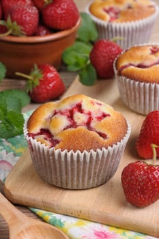 muffin with strawberries on a table among the berries and mint