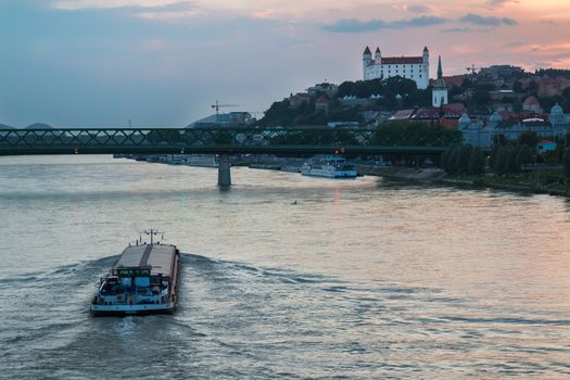 River Danube crossing the city Bratislava in the light of the sunset. View on the old city with the historical cathedral and the castle on the the hill.