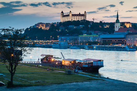 River Danube crossing the city Bratislava in the light of the sunset. View on the old city with the historical cathedral and the castle on the the hill.