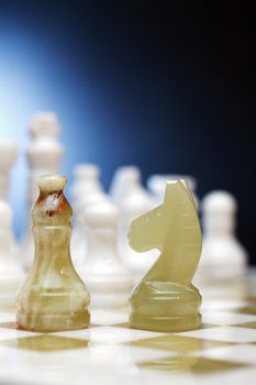 Set of chess pieces made from Onyx on board against dark background